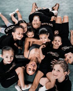 Gruppo di giovani allieve di danza di Outline by OltreDanza a Chivasso, sorridenti e riunite sul pavimento della sala.